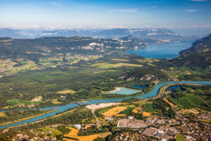 Bassin versant alpin avec lac et rivière, illustrant plusieurs usages de l’eau (habitations, agriculture, industrie) pour la gestion de la ressource.