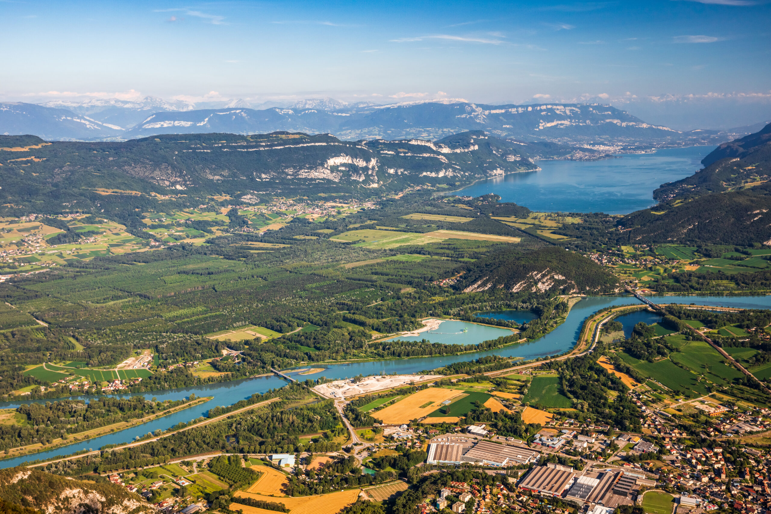 Bassin versant alpin avec lac et rivière, illustrant plusieurs usages de l’eau (habitations, agriculture, industrie) pour la gestion de la ressource.
